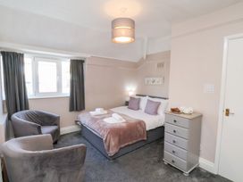 A bedroom with a double bed two chairs a window with curtains and a small chest of drawers at North Beach Lodge in Scarborough