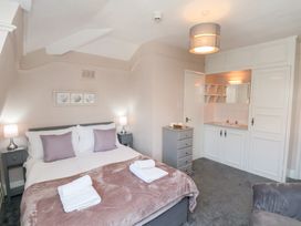 A bedroom with a double bed pillows lamps bedside tables a washbasin unit and a chest of drawers at North Beach Lodge in Scarborough