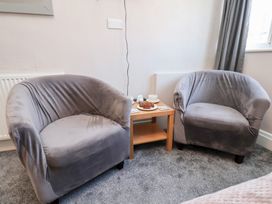 Two gray armchairs with a wooden side table holding tea cups and snacks in a room at North Beach Lodge in Scarborough