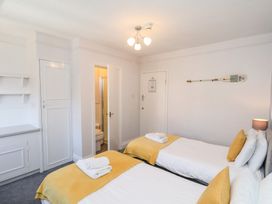 A bedroom with two single beds with yellow blankets and pillows and a small bathroom inside the room at North Beach Lodge in Scarborough