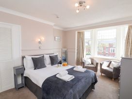 A bedroom with a double bed and two grey chairs by a window at North Beach Lodge in Scarborough