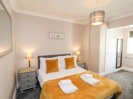 A bedroom with a bed with orange pillows and blanket two bedside tables with lamps and a mirror on the wall at North Beach Lodge in Scarborough