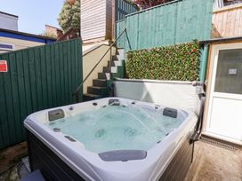 An outdoor hot tub with water jets and green wooden fencing with a small staircase in the background at North Beach Lodge in Scarborough