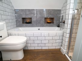 A bathroom with a bathtub, toilet, and shower at Garden View Apartment in Kingsbridge