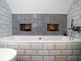 A bathroom with a bathtub and wall tiles at Garden View Apartment in Kingsbridge