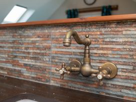 A faucet above a sink with stone tiles at Garden View Apartment in Kingsbridge