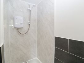 A shower with white walls and a black tiled accent at Avonmede Tewkesbury