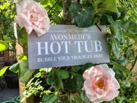 A sign indicating Avonmede's hot tub in a garden with roses in Tewkesbury