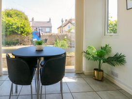 A dining area with a black table and four chairs next to a window and a potted plant in a corner at Westbourne in Llandudno
