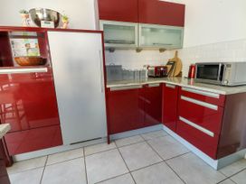 A kitchen with red cabinets a microwave toaster kettle and containers labeled bread biscuits coffee tea and sugar at Westbourne in Llandudno