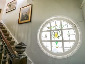 A staircase with carpeted steps wooden banister and a round stained glass window on the wall at Westbourne in Llandudno
