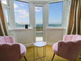 Two pink chairs with a small round table in front of windows overlooking the sea at Westbourne in Llandudno
