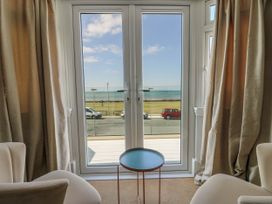 Two beige chairs and a small round table facing double glass doors with a view of the sea at Westbourne in Llandudno