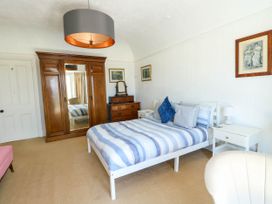 A bedroom with a bed with striped bedding wooden wardrobe and bedside tables at Westbourne in Llandudno