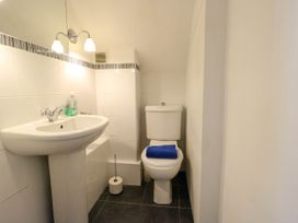 A bathroom with a pedestal sink and a toilet with a blue towel on the seat at Westbourne in Llandudno