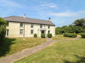 A house with a garden pathway and bushes at Clynnog House in Dwyran near Newborough