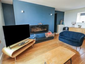 A living room featuring a television and a fireplace at Clynnog House Dwyran near Newborough