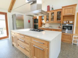 A kitchen with wooden cabinetry and appliances at Clynnog House in Dwyran near Newborough