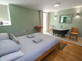 A bedroom with a bed and bathtub at Clynnog House in Dwyran near Newborough