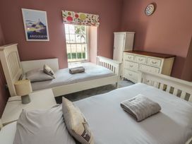 A bedroom with two beds and a chest of drawers at Clynnog House in Dwyran near Newborough