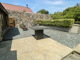 An outdoor area with a stone wall and a table at Clynnog House in Dwyran near Newborough