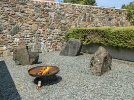 An outdoor space with a fire pit and stones at Clynnog House in Dwyran near Newborough