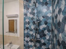 A bathroom with a shower, mirror, and sink at Sail Away, 17 Union Mill, Whitby