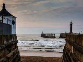 A view of a pier and lighthouse with water at Sail Away, 17 Union Mill in Whitby