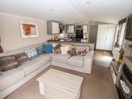 A living room with a beige sectional sofa with patterned cushions and a light wood coffee table at 19 The Brambles in Humberston Lincolnshire