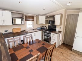 A kitchen with wooden dining table and chairs a stove microwave and countertop appliances at 19 The Brambles in Humberston Lincolnshire