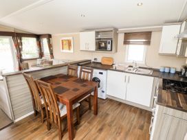 A kitchen and dining area with wooden table and chairs a washing machine microwave and sink at 19 The Brambles in Humberston Lincolnshire