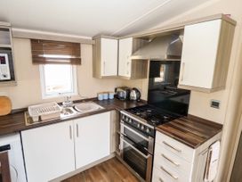 A kitchen with a gas stove, oven, sink, microwave, and kettle at 19 The Brambles in Humberston Lincolnshire