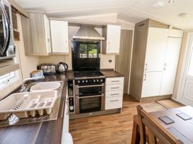 A kitchen with a sink, stove, oven, cabinets, toaster, kettle, and a dining table with chairs at 19 The Brambles in Humberston Lincolnshire