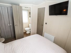 A bedroom with a bed a wall-mounted television two doors and a wardrobe at 19 The Brambles in Humberston Lincolnshire