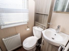 A small bathroom with a toilet sink radiator and window blinds at 19 The Brambles in Humberston Lincolnshire