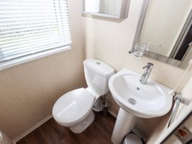 A bathroom with a toilet sink mirror and window blinds at 19 The Brambles in Humberston Lincolnshire