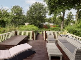An outdoor deck area with wicker furniture and greenery surrounding at 19 The Brambles in Humberston Lincolnshire