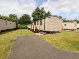 A group of mobile homes on a grassy area with paved paths and trees in the background at 19 The Brambles in Humberston Lincolnshire