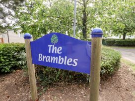 Blue sign with the text The Brambles surrounded by trees and bushes at 19 The Brambles in Humberston Lincolnshire