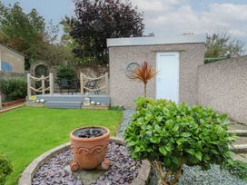A garden with a flower pot, plants and a deck at Glasfryn in Holyhead