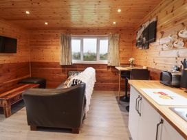 A living room with a sofa and kitchen counter at Stag Lodge Pod Llanfair Caereinion