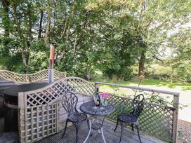 An outdoor area with a hot tub and a table with chairs at Stag Lodge Pod in Llanfair Caereinion
