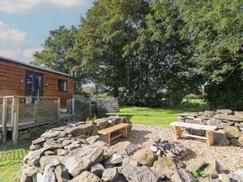 An outdoor area with wooden benches and a fire pit at Stag Lodge Pod Llanfair Caereinion