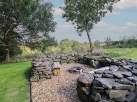 An outdoor space with a stone circle fire pit and a wooden bench at Stag Lodge Pod Llanfair Caereinion