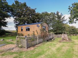 A wooden cabin with a deck and trees at Stag Lodge Pod Llanfair Caereinion