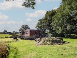 A house surrounded by grass and trees at Stag Lodge Pod in Llanfair Caereinion