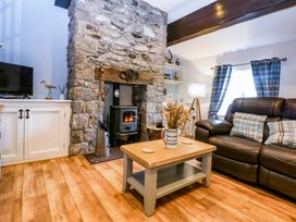 A living room with a fireplace and sofa at Cosy Cottage in Llandegfan near Menai Bridge