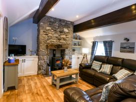 A living room with a stone fireplace and sofa at Cosy Cottage Llandegfan near Menai Bridge