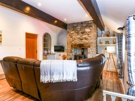 A living room with a leather sofa and a stone fireplace at Cosy Cottage in Llandegfan near Menai Bridge