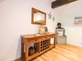 A console table with a mirror and vase at Cosy Cottage in Llandegfan near Menai Bridge
